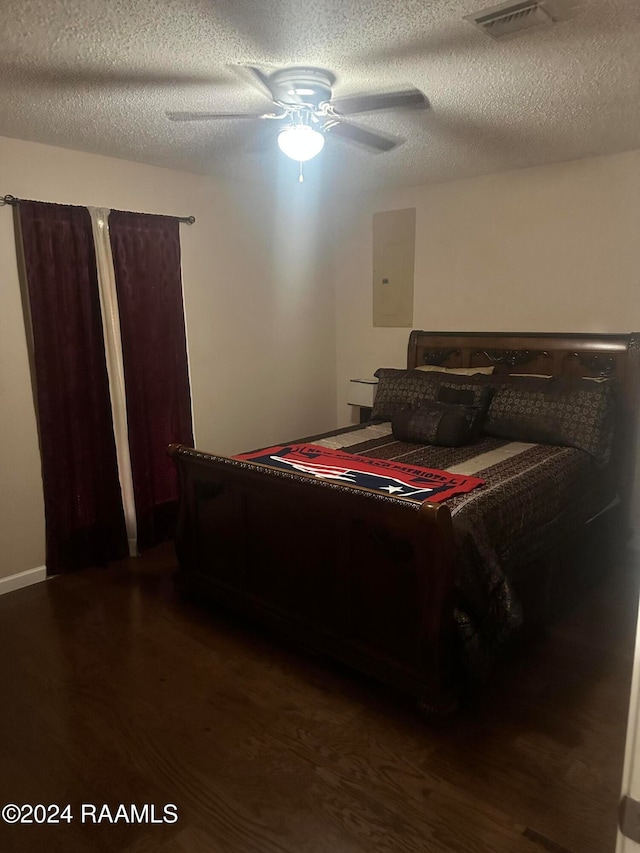 bedroom featuring electric panel, ceiling fan, dark wood-type flooring, and a textured ceiling