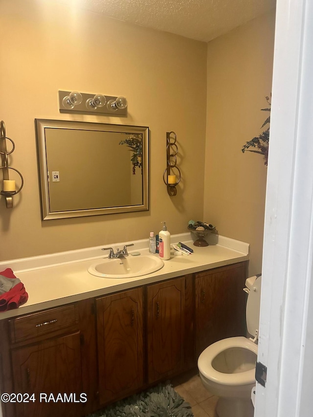 bathroom featuring tile patterned flooring, vanity, a textured ceiling, and toilet