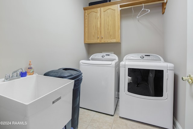 clothes washing area with washer and clothes dryer, light tile patterned floors, cabinets, and sink