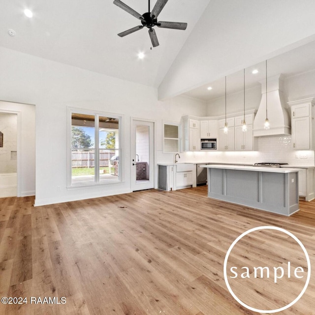 kitchen with pendant lighting, premium range hood, white cabinets, light hardwood / wood-style flooring, and stainless steel appliances