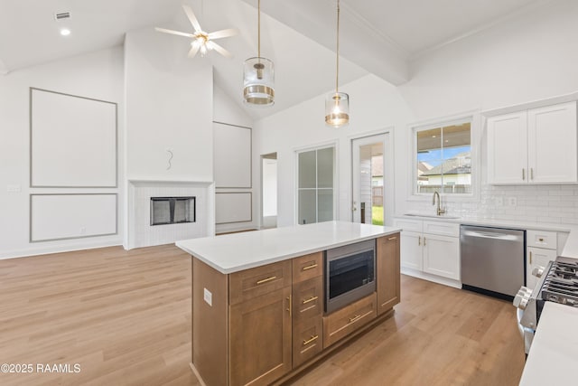 407 Sunshine Rise Dr, Broussard, LA 70518 - kitchen featuring appliances with stainless steel finishes, white cabinets, light wood-style flooring, light countertops, and backsplash