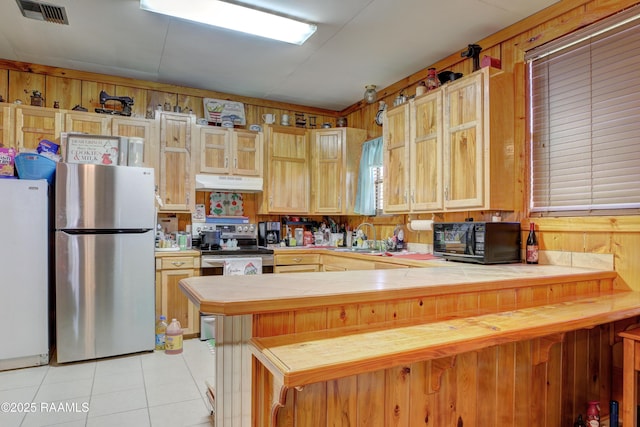 kitchen featuring kitchen peninsula, sink, light tile patterned floors, and appliances with stainless steel finishes