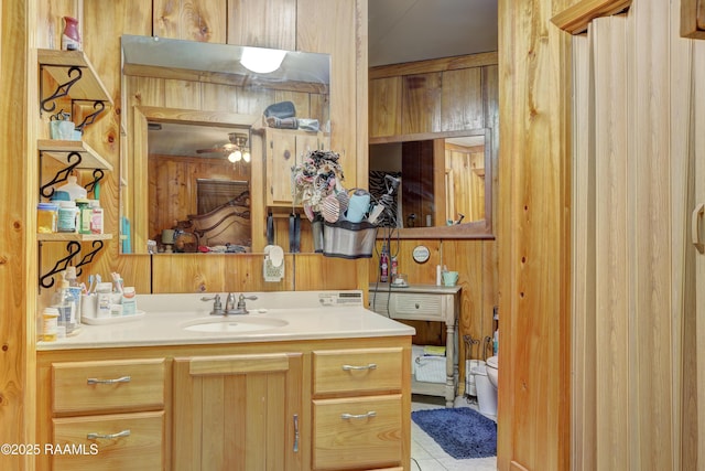 bathroom featuring ceiling fan, wooden walls, vanity, and toilet