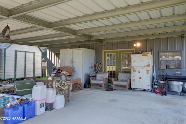 garage with white refrigerator and wooden walls