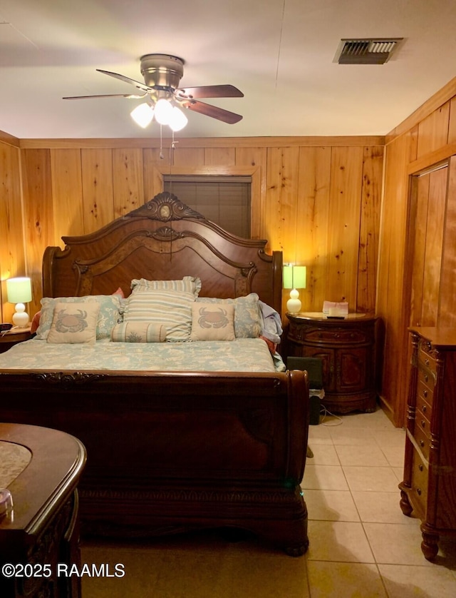 bedroom featuring ceiling fan, light tile patterned floors, and wooden walls