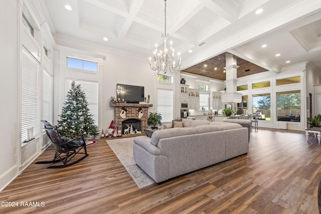 living room featuring coffered ceiling, a brick fireplace, a towering ceiling, a chandelier, and hardwood / wood-style flooring