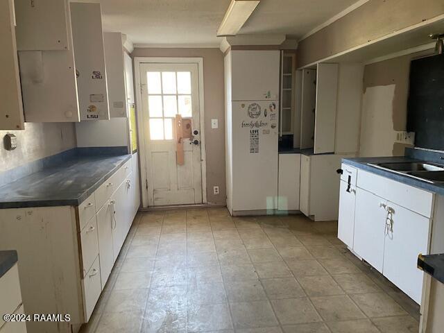 kitchen with crown molding, white cabinetry, and sink