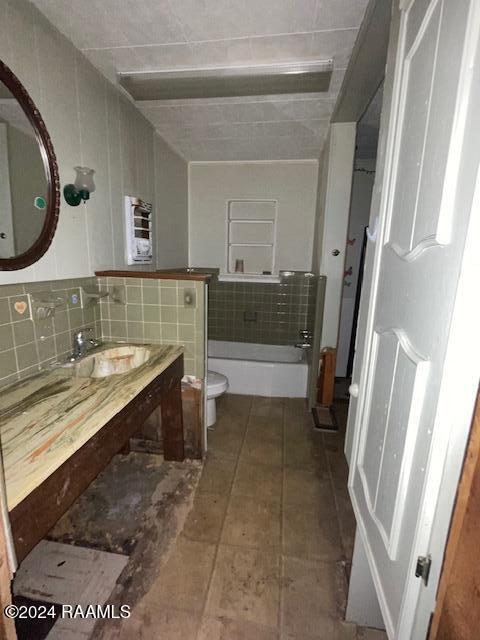 bathroom with tile patterned floors, sink, a washtub, toilet, and tasteful backsplash