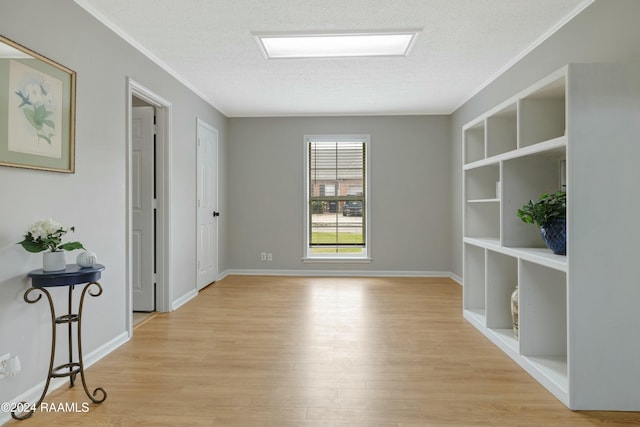 spare room featuring ornamental molding, a textured ceiling, and light wood-type flooring