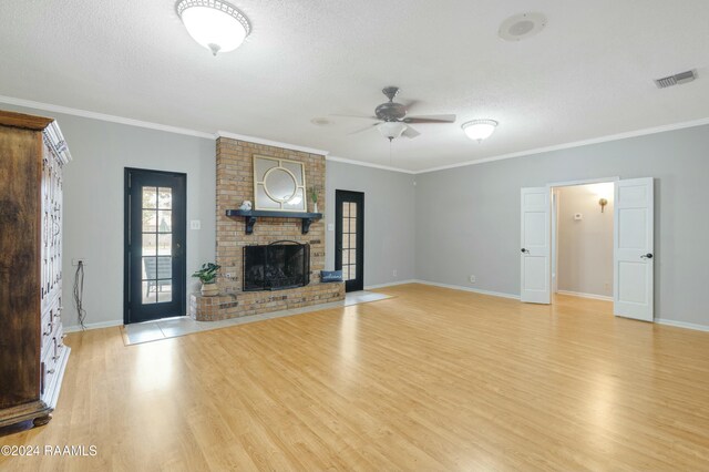 unfurnished living room featuring ceiling fan, light wood-type flooring, a textured ceiling, a fireplace, and ornamental molding