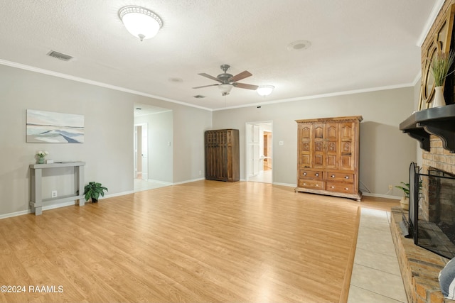 living room featuring crown molding, ceiling fan, a textured ceiling, a fireplace, and light hardwood / wood-style floors