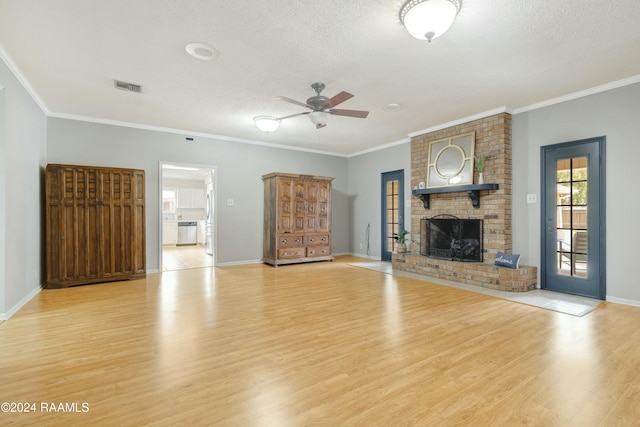 unfurnished living room featuring ceiling fan, light wood-type flooring, a textured ceiling, a fireplace, and ornamental molding