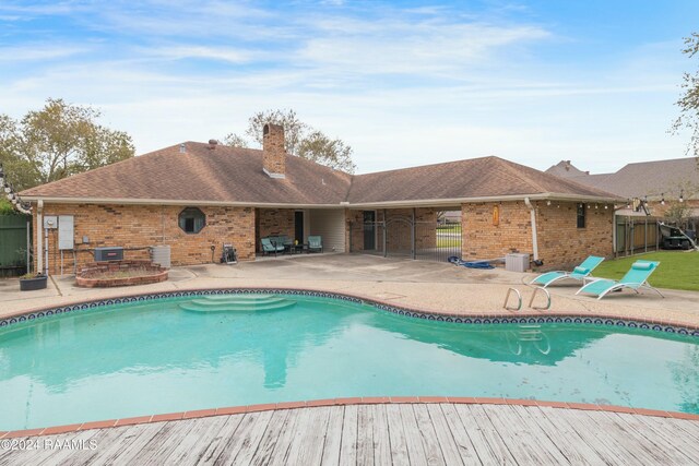 view of swimming pool with grilling area, cooling unit, and a patio area