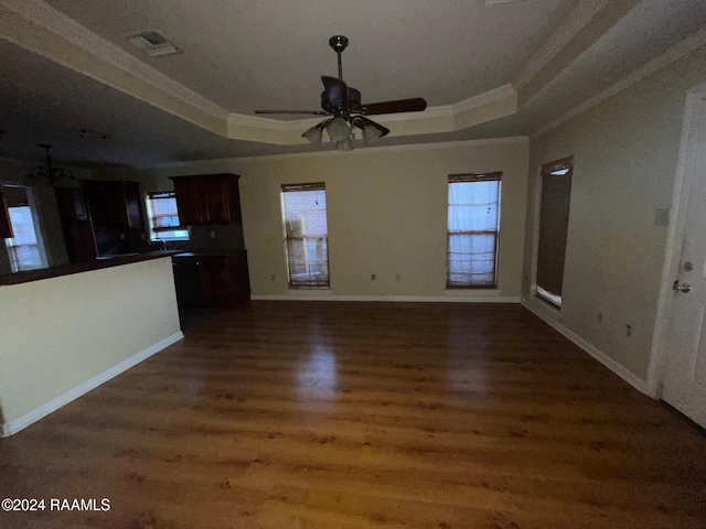 unfurnished living room featuring a raised ceiling, ceiling fan, dark hardwood / wood-style floors, and ornamental molding