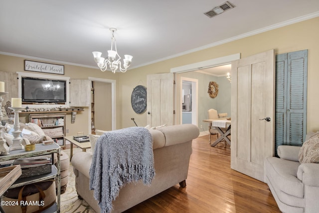 living room with hardwood / wood-style flooring, crown molding, and a notable chandelier