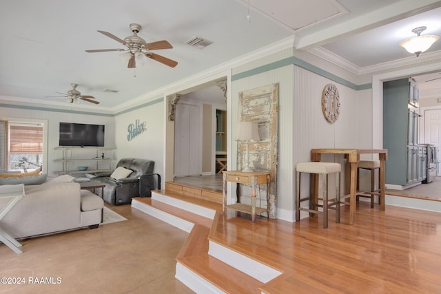 living room with light hardwood / wood-style flooring, ceiling fan, and ornamental molding