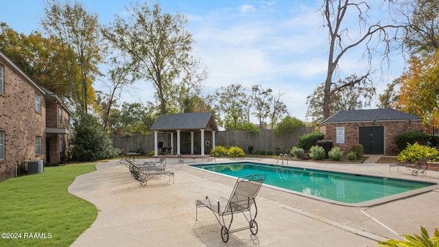 view of swimming pool with an outdoor structure, a patio, and central air condition unit