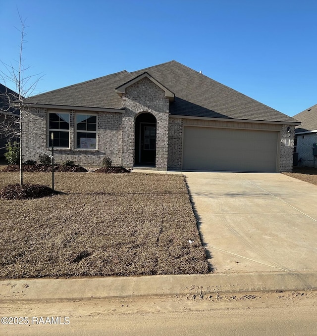 view of front of house featuring a garage, concrete driveway, brick siding, and roof with shingles