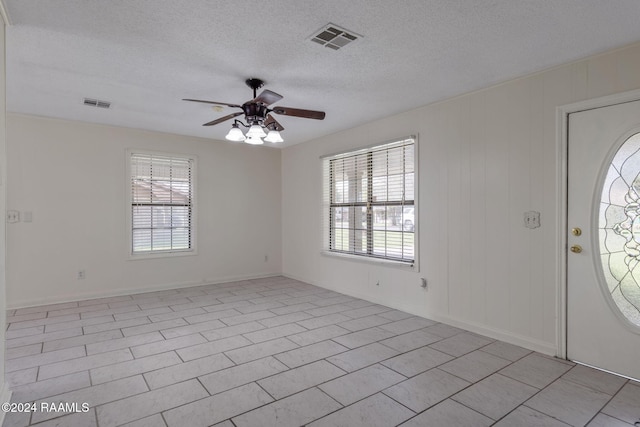 foyer entrance featuring ceiling fan, light tile patterned floors, a healthy amount of sunlight, and a textured ceiling