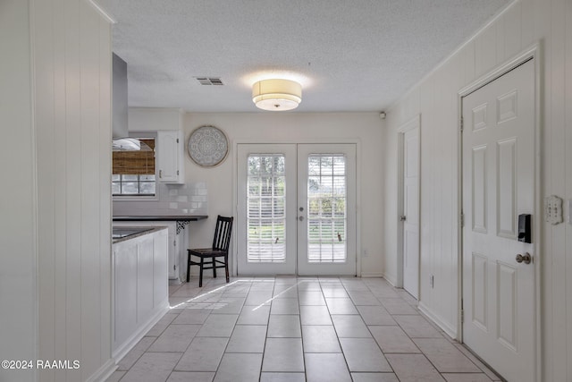 entryway featuring french doors, a textured ceiling, and light tile patterned floors