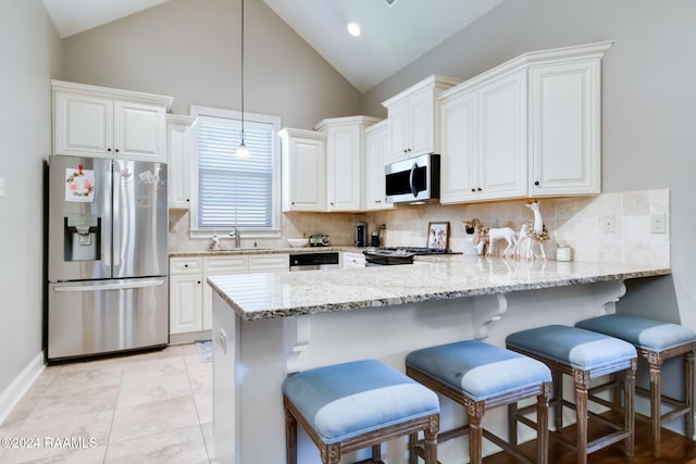 kitchen with white cabinets, a breakfast bar area, decorative light fixtures, kitchen peninsula, and stainless steel appliances