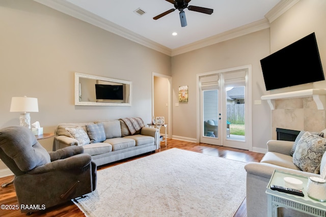 living room with crown molding, ceiling fan, hardwood / wood-style floors, and a tile fireplace