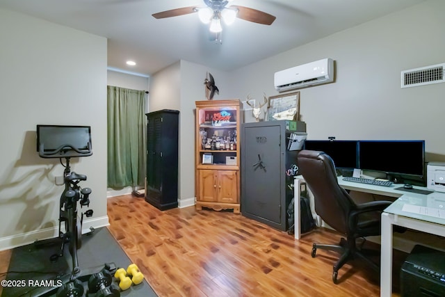 office space featuring hardwood / wood-style flooring, ceiling fan, and an AC wall unit