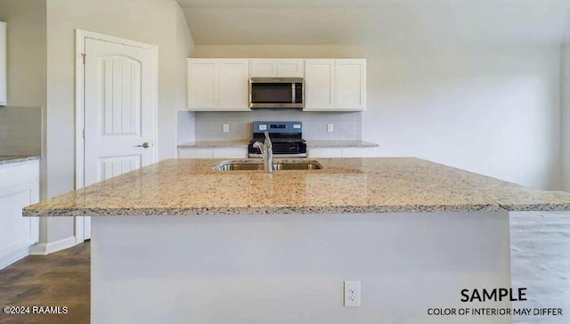 kitchen with appliances with stainless steel finishes, white cabinetry, a kitchen island with sink, and light stone counters