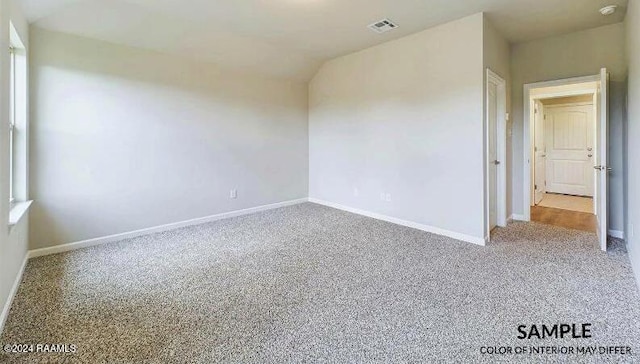 carpeted empty room featuring lofted ceiling