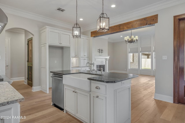 kitchen with white cabinets, an island with sink, stainless steel dishwasher, and sink