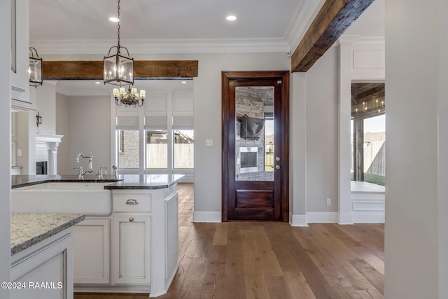 kitchen featuring ornamental molding, sink, pendant lighting, light hardwood / wood-style flooring, and white cabinets