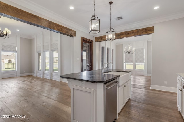 kitchen with white cabinetry, decorative light fixtures, hardwood / wood-style flooring, a center island with sink, and ornamental molding