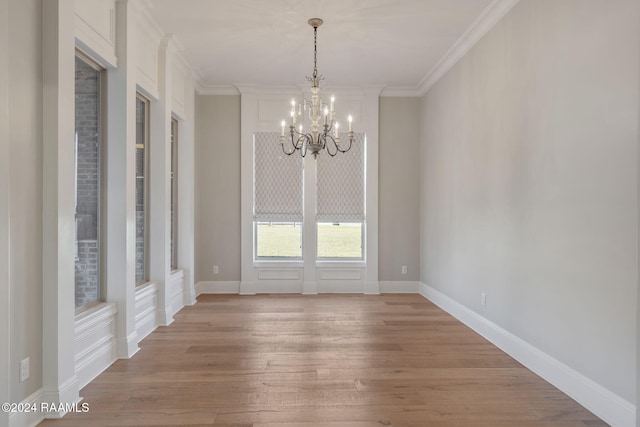 unfurnished dining area featuring crown molding, wood-type flooring, and an inviting chandelier