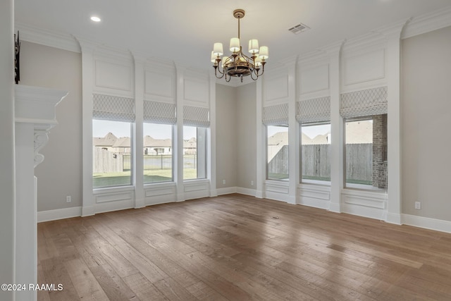 unfurnished room with wood-type flooring, crown molding, and an inviting chandelier