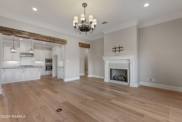 unfurnished living room featuring crown molding, light hardwood / wood-style floors, and a notable chandelier