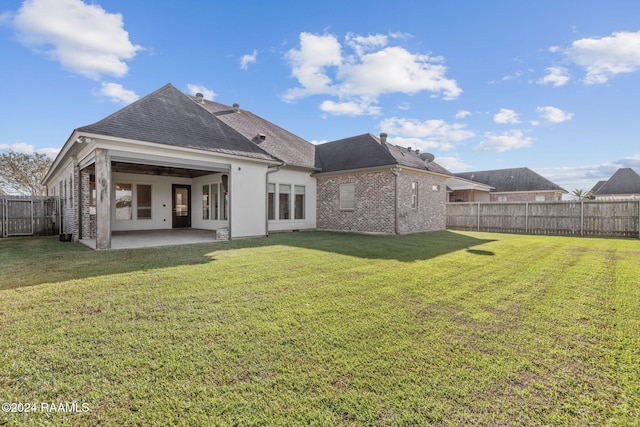 rear view of property featuring a lawn and a patio area