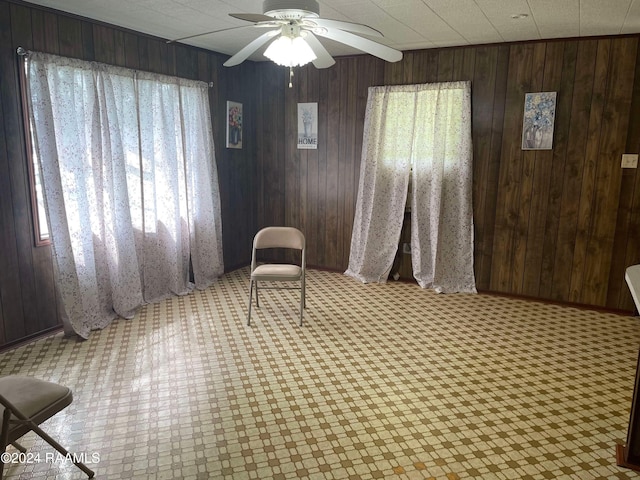 sitting room featuring a healthy amount of sunlight, ceiling fan, and wooden walls