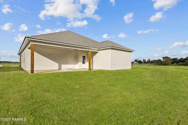 back of house with a yard, roof with shingles, and a patio