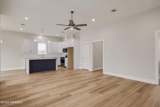 unfurnished living room with ceiling fan, sink, and light wood-type flooring