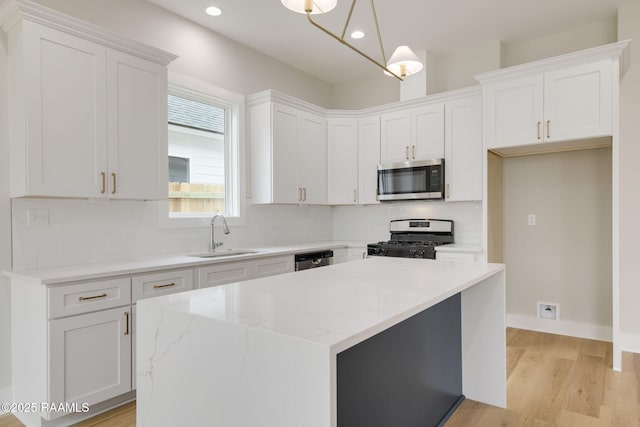 kitchen featuring sink, white cabinetry, a center island, stainless steel appliances, and light stone countertops