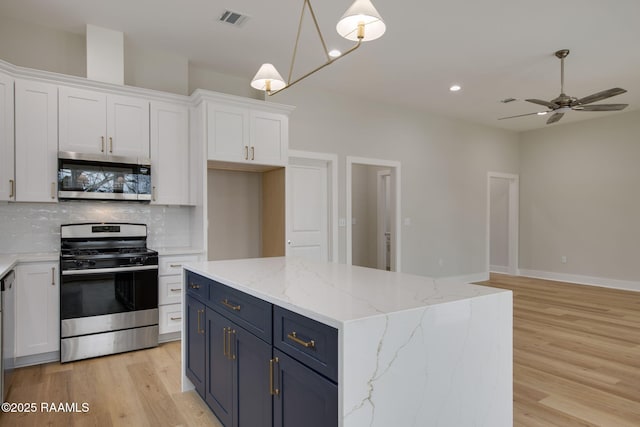 kitchen featuring pendant lighting, blue cabinets, white cabinets, decorative backsplash, and stainless steel appliances