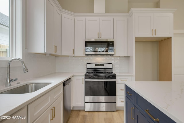 kitchen with white cabinetry, appliances with stainless steel finishes, blue cabinets, and sink