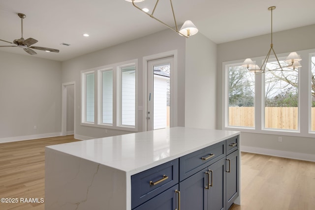 kitchen with pendant lighting, light hardwood / wood-style floors, light stone counters, and a wealth of natural light