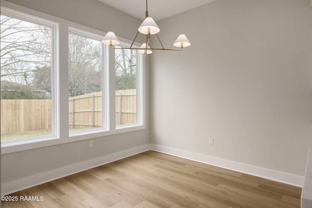 unfurnished dining area with a chandelier and light wood-type flooring