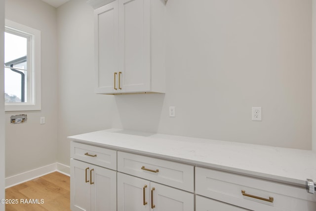 interior space featuring light stone countertops, light hardwood / wood-style floors, and white cabinets