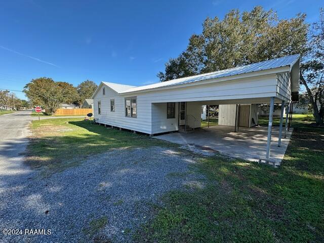 1722 Michael St, Abbeville, LA 70510 - view of home's exterior featuring a metal roof, driveway, and a lawn