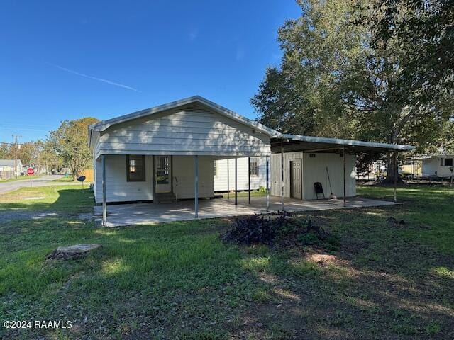 rear view of property featuring a lawn and a carport