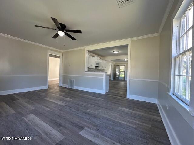 unfurnished living room with ceiling fan, a healthy amount of sunlight, dark hardwood / wood-style flooring, and crown molding