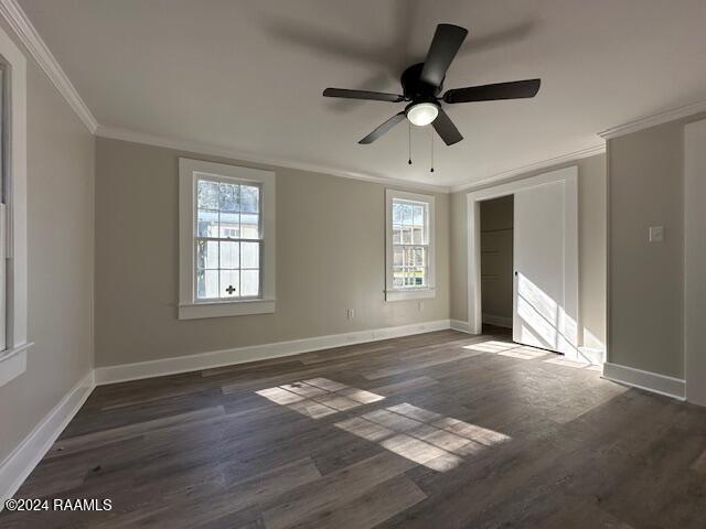 unfurnished bedroom with ceiling fan, dark hardwood / wood-style floors, ornamental molding, and multiple windows