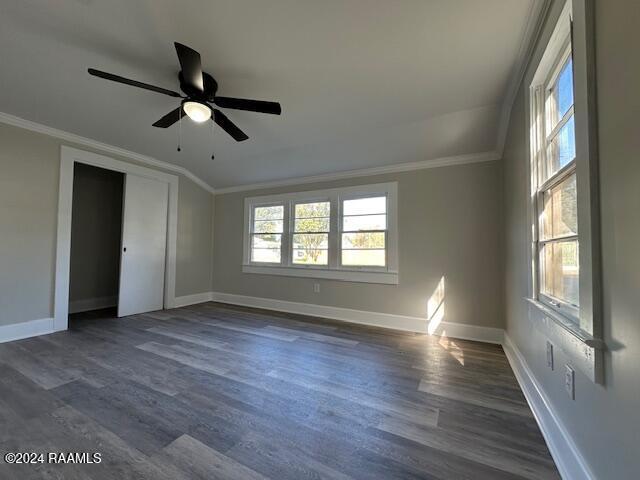 empty room featuring ceiling fan, dark hardwood / wood-style flooring, ornamental molding, and lofted ceiling